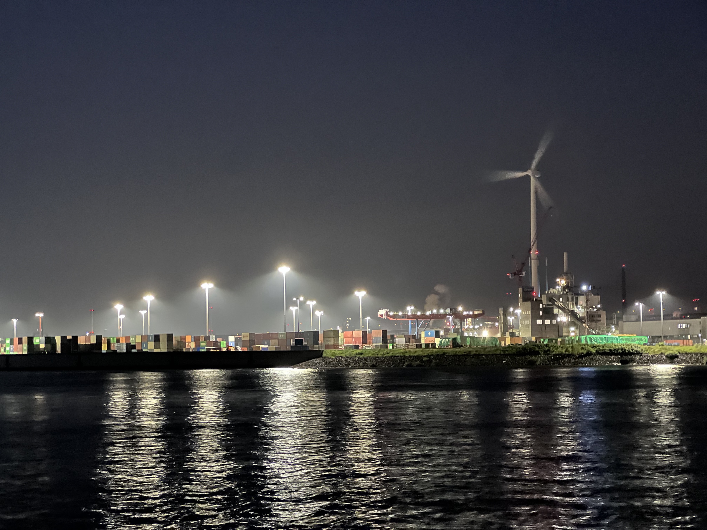 Container yard at night with wind turbine